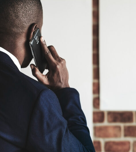 Businessman talking on phone, brick wall background.