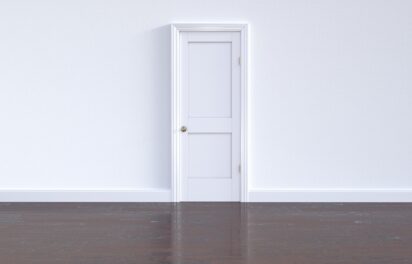 White door with white wall and wooden floor White door with white wall and wooden floor